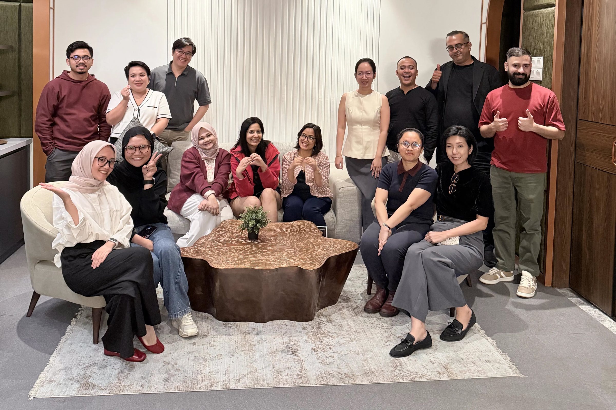 The Parent Inc leadership team together in a lounge, some seated around a table and others standing behind